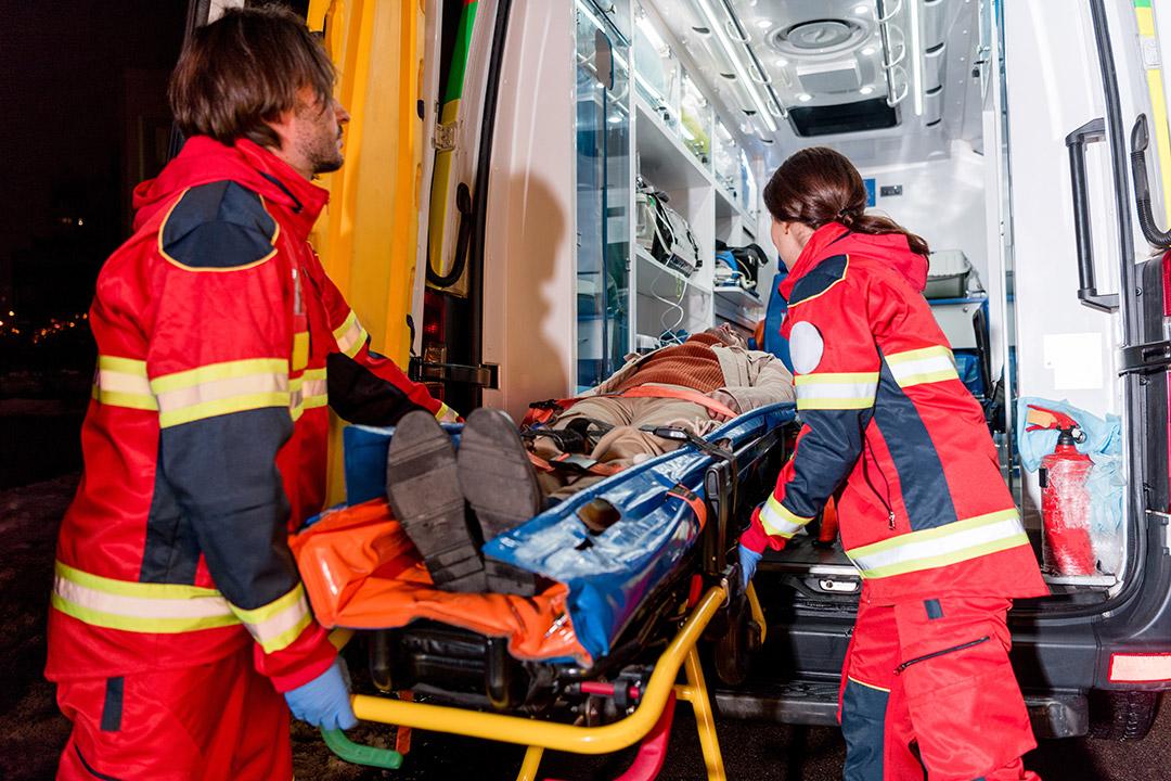 A patient on a stretcher being placed in a ground ambulance