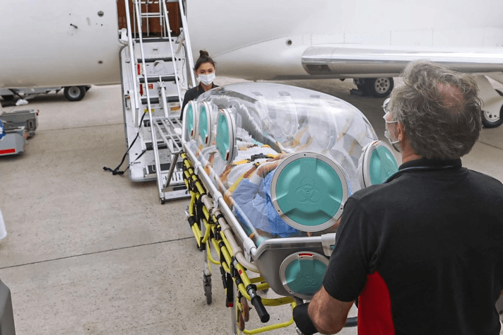 A patient being carried in an isolation pod